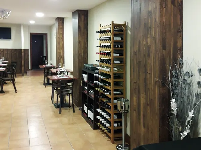 Pilares de madera oscura y botellero en la sala
