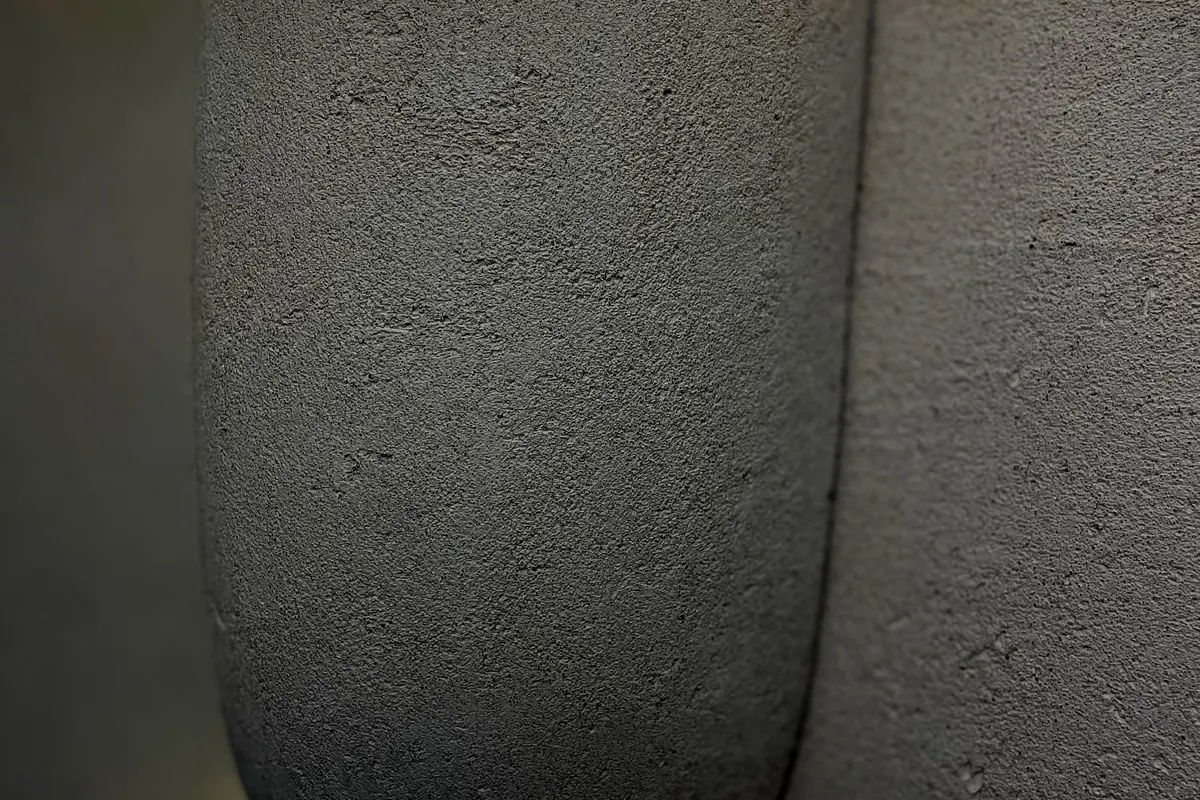 Detalle de textura mineral de cal junto a un aplique de pared